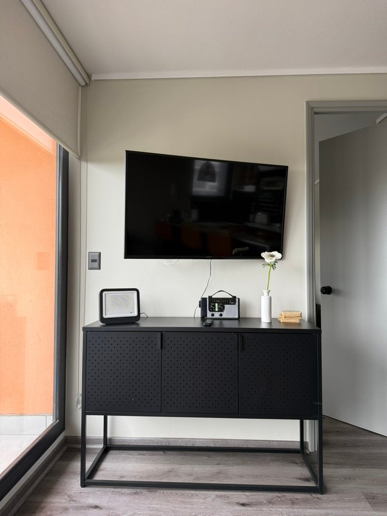 Televisión y mueble del living junto al balcón del departamento