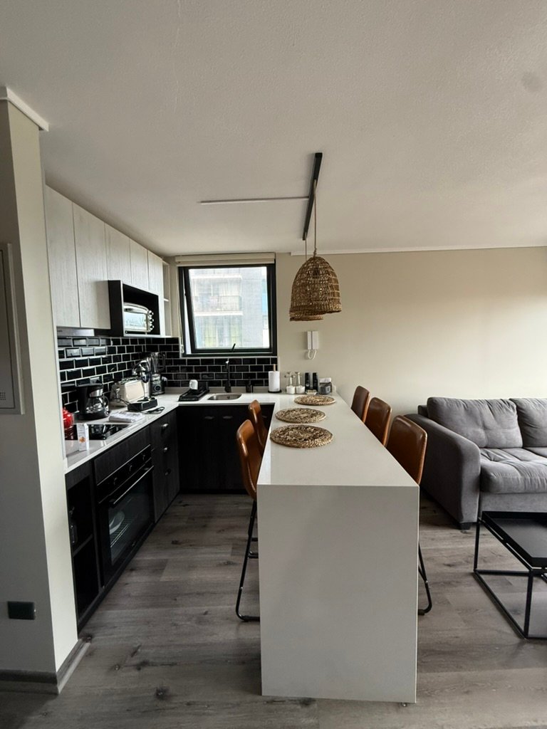 Cocina equipada con barra comedor y living en departamento de Valparaíso